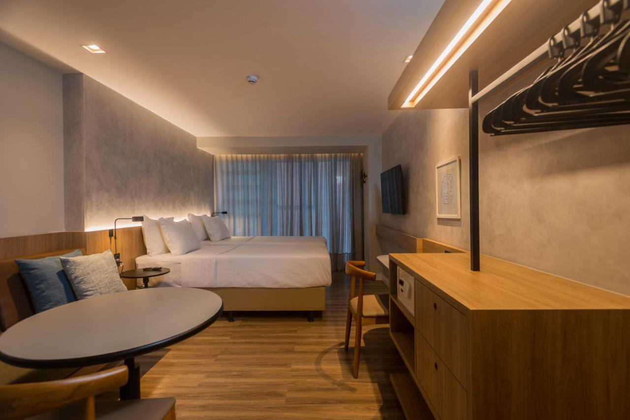 Hotel Luzeiros Fortaleza 외부 사진 The photo shows a modern hotel room with a clean and minimalist design. It features two large beds with light-colored bedding, positioned against a wall with a textured finish. There are large windows with sheer curtains allowing natural light to fil