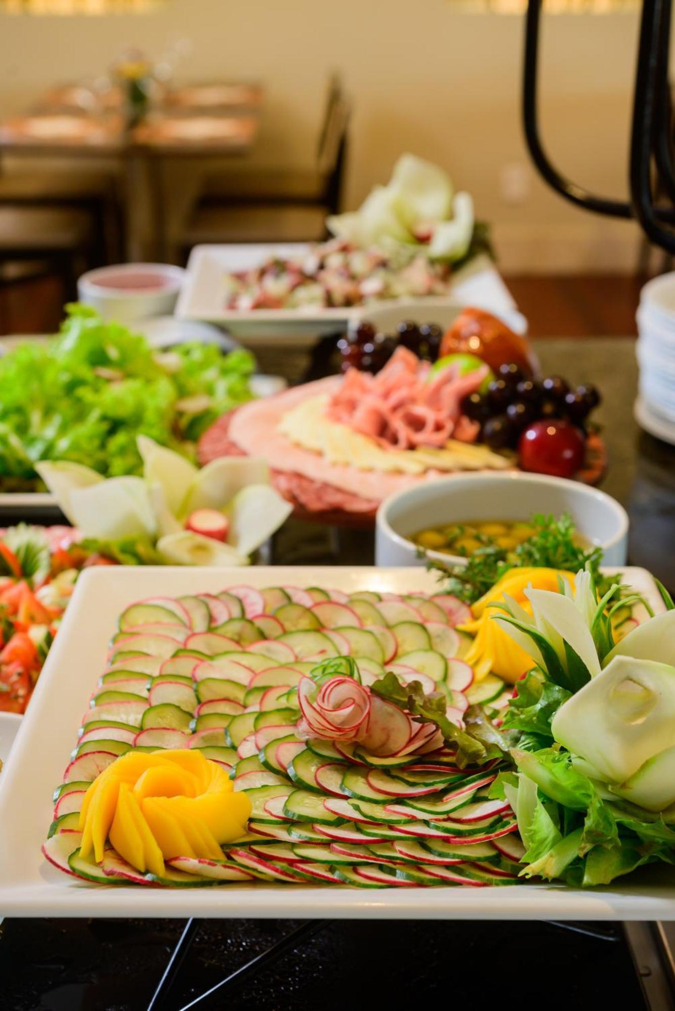 Hotel Luzeiros Fortaleza 외부 사진 The photo showcases a beautifully arranged display of food. In the foreground, there's a plate with thinly sliced cucumbers arranged in a decorative pattern, garnished with leafy greens and edible flowers. Surrounding this plate are various other dis