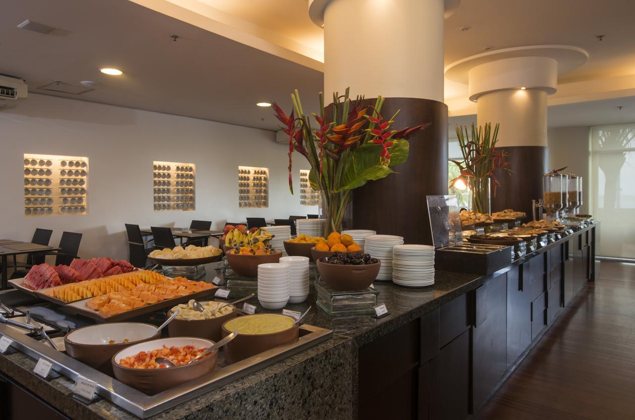 Hotel Luzeiros Fortaleza 외부 사진 The photo displays a buffet setup in a dining area. On the counter, there are various dishes arranged attractively. You can see a colorful assortment of fruits and salads, including slices of watermelon and other fruits. There are also several bowls 