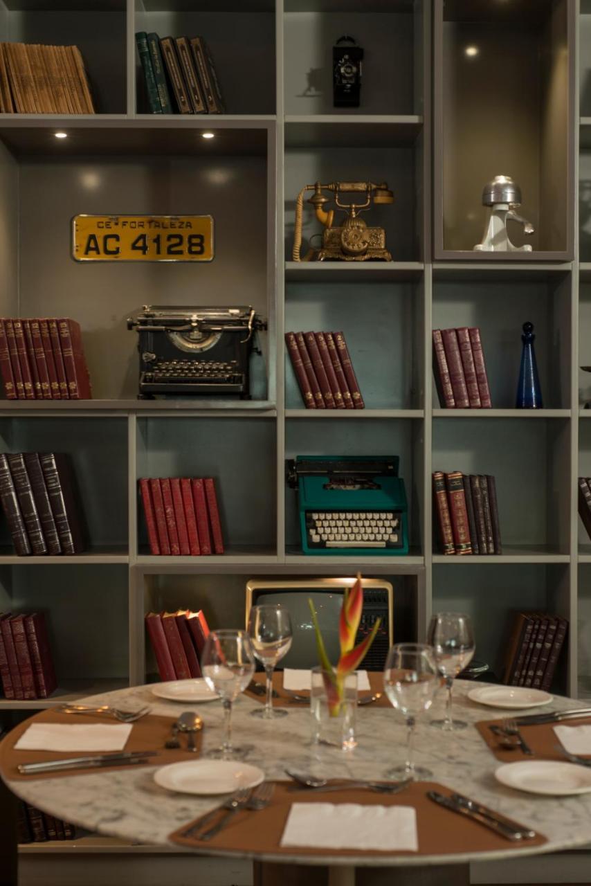 Hotel Luzeiros Fortaleza 외부 사진 The photo features a vintage-inspired bookshelf with a grid design. It showcases several items, including:

- Old typewriters, one in black and one in green.
- A collection of books with red covers stacked upright.
- An antique television set.
- A bl